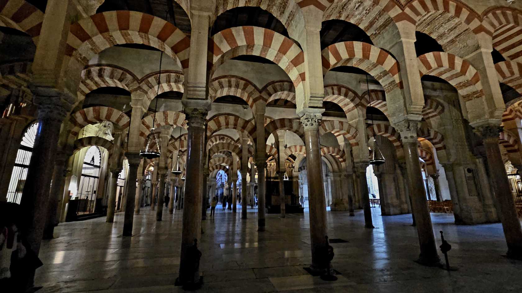 Innenraum einer Moschee mit Marmorsäulen, die rot-weiss-gestreifte Bögen in der tragen.